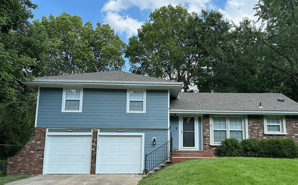 Angled shot of blue house with James Hardie siding with a brick chimney on the right side.