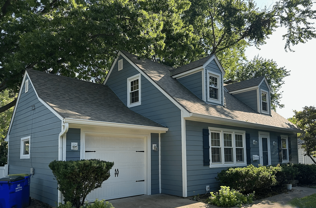 Angled shot of blue house with James Hardie siding with a brick chimney on the right side.